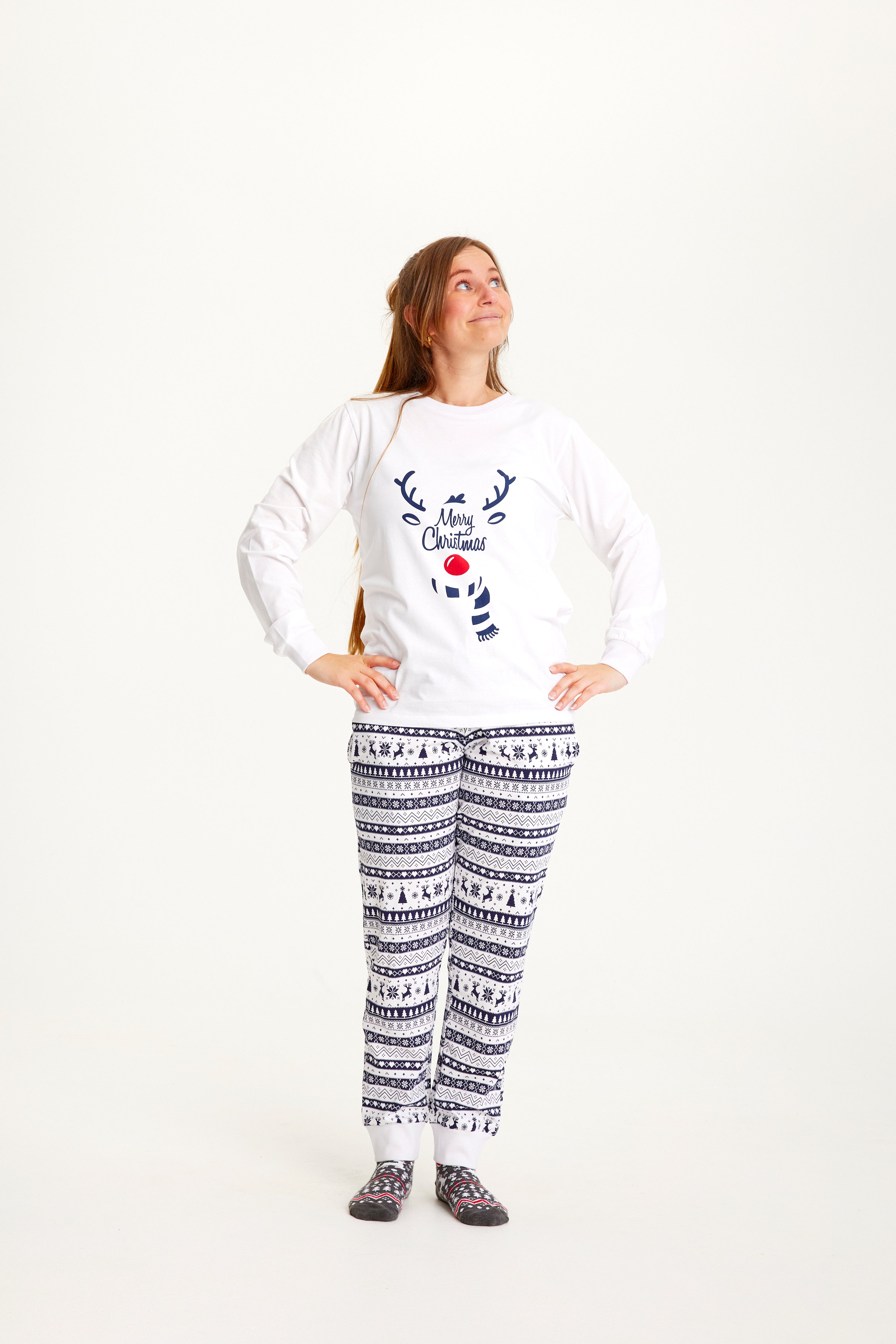 Une femme, les mains le long du corps, vêtue d'un pyjama de Noël blanc.